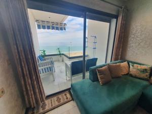 een woonkamer met een groene bank en een groot raam bij Cosy Appartement meublé à Mehdia in Kenitra