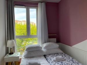 sypialnia z łóżkiem z oknem i białymi poduszkami w obiekcie Apartamenty Warszawa Centrum Włodarzewska 30 m45 w Warszawie