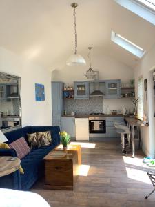 a living room with a blue couch and a kitchen at Tigh Noor - Escape to Kinvara by the sea! in Galway
