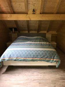 a bed in a room with a wooden ceiling at Forest Jura Lodge - Chalet de la Vache in Alièze