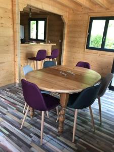una mesa de madera con sillas moradas en una cabaña en Forest Jura Lodge - Chalet de la Vache, en Alièze