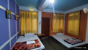two beds in a room with yellow curtains at Khowti Stay in Dirang Dzong