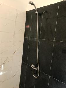 y baño con ducha y azulejos blancos y negros. en Viesu nams Baņuta1, en Saulkrasti