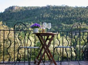 a table with two chairs and wine glasses on a balcony at L’Hacienda Maison d’hôtes in Bagnols-en-Forêt