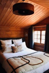 - une chambre avec un grand lit et un plafond en bois dans l'établissement L’Hacienda Maison d’hôtes, à Bagnols-en-Forêt