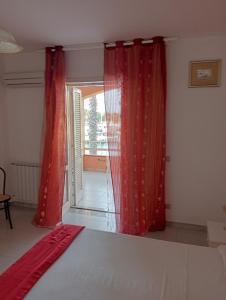 una camera da letto con tende rosse, un letto e una finestra di trilocale "Alicudi" in Portorosa a Furnari