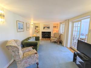 een woonkamer met een bank en stoelen en een televisie bij Rose Cottage in Bembridge