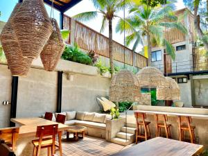 a patio with a couch and tables and palm trees at Nectar Hotel, Cafe, Cowork - Adults Only in Puerto Escondido