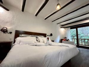 una camera da letto con un grande letto bianco con cuscini bianchi di Hatun Inti Boutique a Machu Picchu