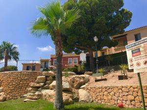 eine Palme in einem Hof neben einer Steinmauer in der Unterkunft Casita El Mirador in Cala de Finestrat