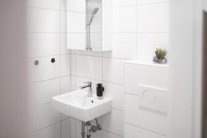 La salle de bains blanche est pourvue d'un lavabo et d'un miroir. dans l'établissement Koje Drei I Zentrales Apartment mit Parkplatz, à Bremerhaven
