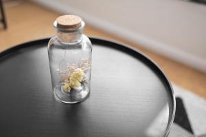 a glass bottle with flowers in it sitting on a table at Koje Drei I Zentrales Apartment mit Parkplatz in Bremerhaven