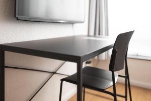 a black desk with a chair and a television at Koje Drei I Zentrales Apartment mit Parkplatz in Bremerhaven +9 photos