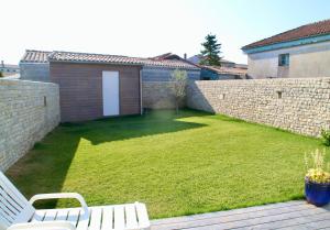 a yard with two white benches and a brick wall at Le vieux chai in Sainte-Marie-de-Ré