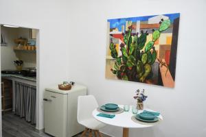 una cocina con una mesa y una pintura de cactus en la pared en Jolie Maison, en Brindisi