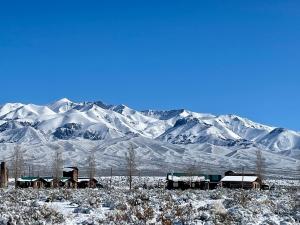 a snow covered mountain range with houses in the foreground at Cabañas NAOL in Uspallata