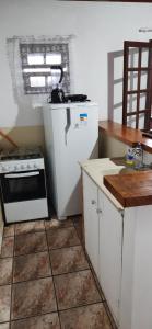a kitchen with a stove and a white refrigerator at Chalé do Radiola in Ilhabela