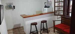 a kitchen with two stools and a counter with a window at Chalé do Radiola in Ilhabela