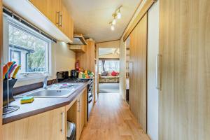 eine Küche mit Holzschränken, einem Waschbecken und einem Fenster in der Unterkunft Sandcastle Mobility Lodge in Christchurch