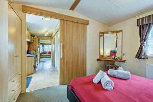 a bedroom with a red bed and a kitchen at Sandcastle Mobility Lodge in Christchurch