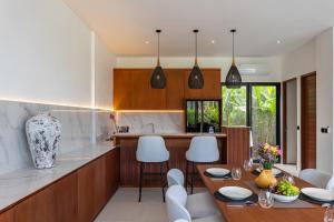 a kitchen with a wooden table and white chairs at Aquamarine Villa 1 Canggu in Canggu