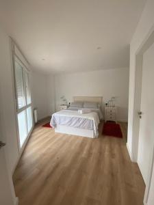 a white bedroom with a bed and a wooden floor at Chalet en Aldán in Cangas de Morrazo