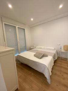 a white bedroom with a bed and two windows at Chalet en Aldán in Cangas de Morrazo