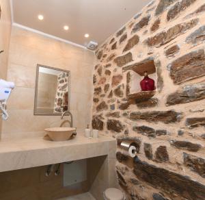 uma casa de banho em pedra com um lavatório e uma parede de pedra em Marmari Paradise Resort Hotel em Marmari