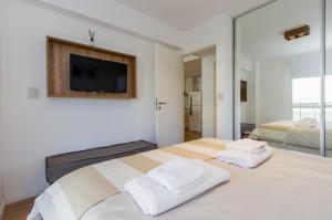 1 Schlafzimmer mit 2 Betten und einem TV an der Wand in der Unterkunft Gray Fox Apartments Pipo in Ushuaia