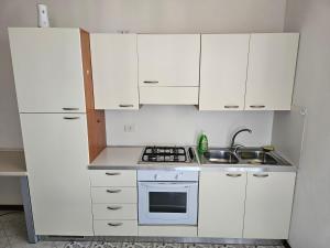 eine kleine Küche mit weißen Schränken und einem Waschbecken in der Unterkunft Appartamento a Porto Garibaldi vicino al mare in Porto Garibaldi
