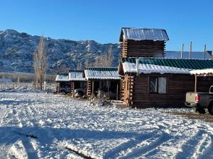 a log cabin in the snow with mountains in the background at Cabañas NAOL in Uspallata