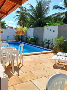 a patio with white chairs and a swimming pool at JACY AP GOSTOSO in São Miguel do Gostoso