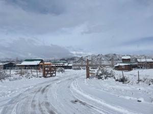 polna droga pokryta śniegiem obok domów w obiekcie Cabañas NAOL w mieście Uspallata