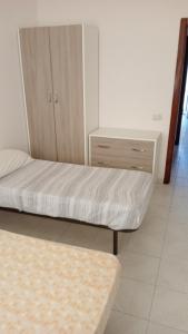 una camera con un letto e un comò di trilocale "Lipari" in Portorosa a Torre Forte