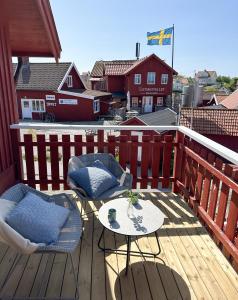 una terrazza in legno con tavolo e sedie sul balcone. di Hotell Käringön a Käringön