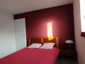 Cottage à 2 mn à pied de la mer في ميرفيل-فرانسفيل بلاج: غرفة نوم حمراء مع سرير بجدار احمر