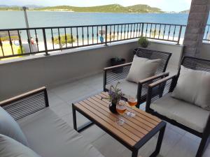 un balcón con 2 sillas y una mesa con bebidas. en Apartmani Šara 2, en Betina