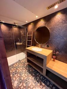 a bathroom with a sink and a mirror and a shower at Les Baroudeurs de Saint Jean in Saint-Jean-de-Barrou