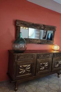 um vaso sentado em cima de uma cómoda com um espelho em Rez de maison/jacuzzi privé/patio fleuri em Olivese