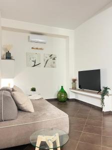 uma sala de estar com um sofá e uma televisão de ecrã plano em La casa di Apollo em Acireale