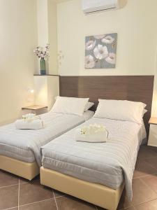 2 Einzelbetten in einem Schlafzimmer mit Blumen darauf in der Unterkunft La casa di Apollo in Acireale