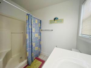 a bathroom with a shower with a blue shower curtain at Salt, Sand and Sudds home in Holden Beach
