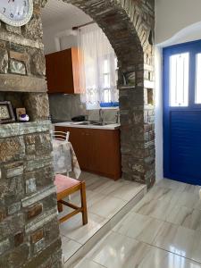 To Paradosiako في سيريفوس شورا: مطبخ بباب ازرق وجدار حجري