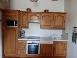 PouzacにあるBel appartement rénové dans maison bigourdaneのキッチン(木製キャビネット、シンク、電子レンジ付) +4枚の写真