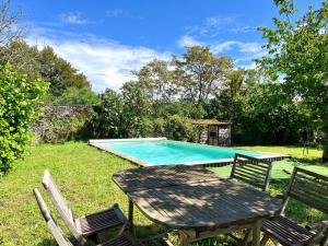 a picnic table and chairs next to a swimming pool at Au Domaine Valigny, piscine chauffée + WIFI Fibre in Saint-Benoît