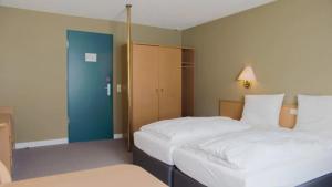 a bedroom with two beds and a blue door at Hotel Bitburg in Bitburg