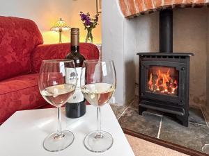 due bicchieri di vino su un tavolo di fronte al camino di Allington Cottage a Bridport
