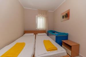 - 2 lits dans une petite chambre avec des draps jaunes dans l'établissement Beach apartments, à Petrovac na Moru