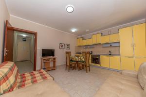 un salon avec une table et une cuisine avec des armoires jaunes dans l'établissement Beach apartments, à Petrovac na Moru