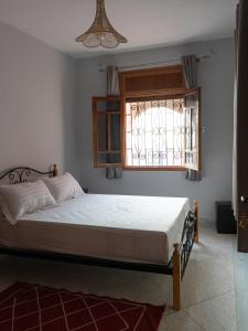 1 dormitorio con cama y ventana en Santacruz Hostel, en Tamraght Ouzdar
